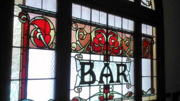 Una vidriera con la palabra "BAR" en el centro, rodeada de motivos florales decorativos.