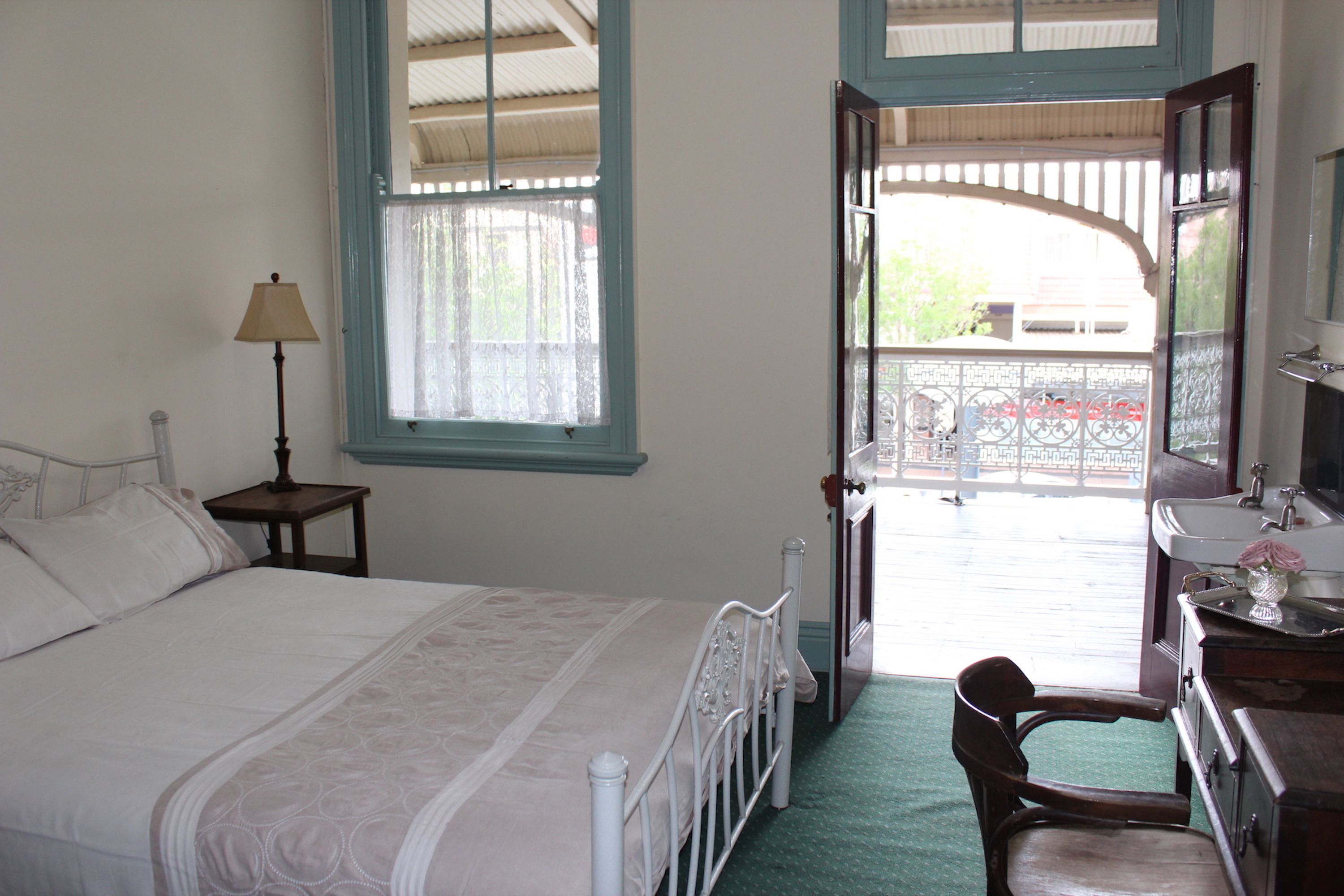 Une chambre à coucher comprenant un lit, une table de chevet, une chaise, une commode, un miroir et une fenêtre donnant sur l’extérieur.