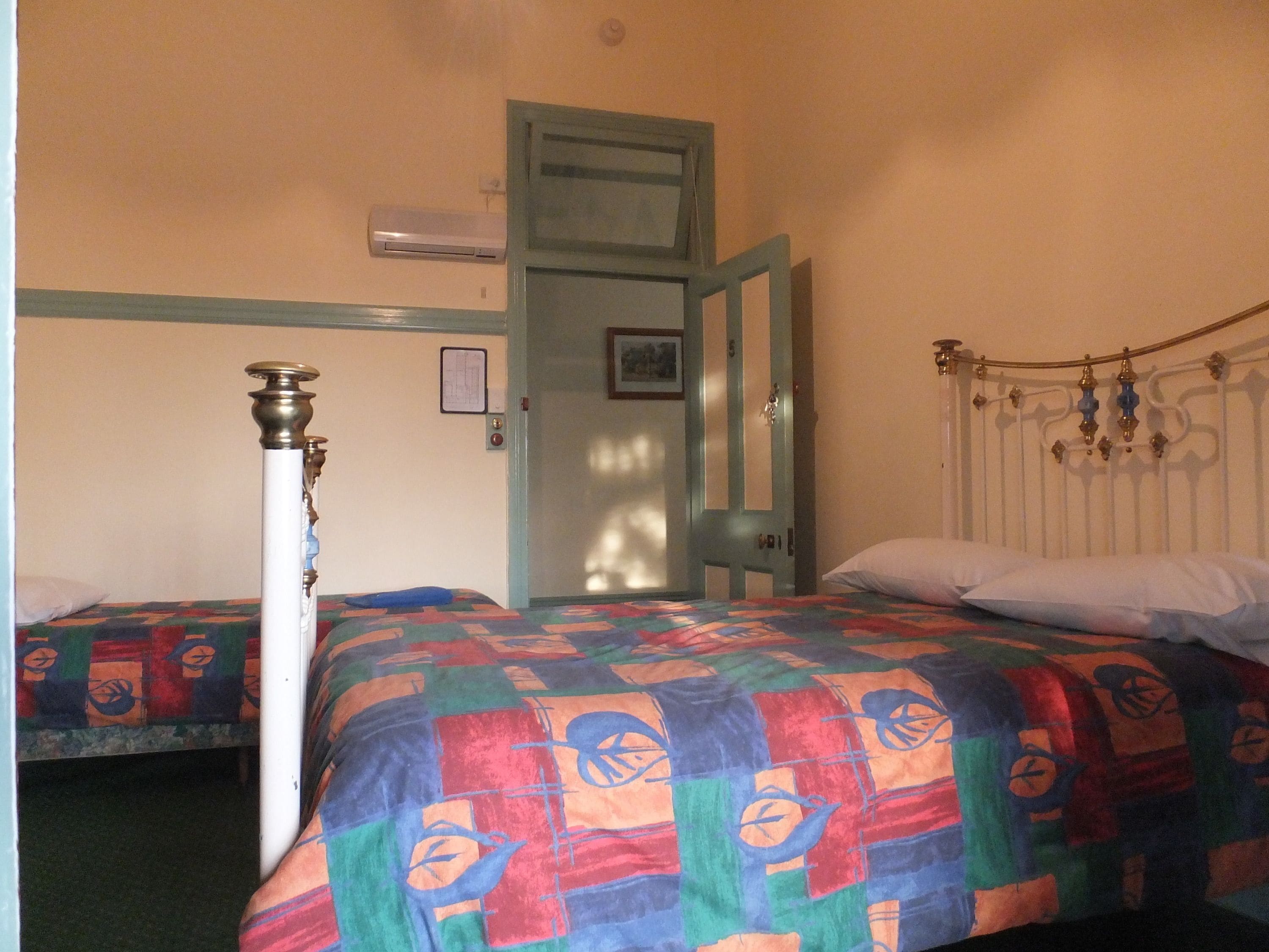 A bedroom with two beds, a door, and a radiator.