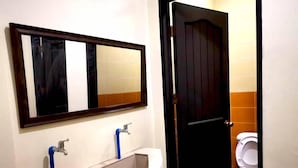 A bathroom with a large mirror, a bathtub, and a toilet. - The Stopover Hostel Mactan (Lapu-Lapu)