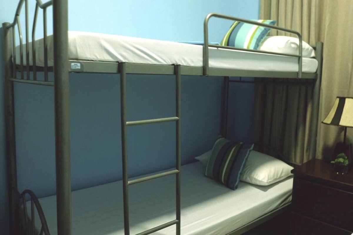 Un lit superposé avec une échelle, un oreiller et une table de chevet avec une lampe.