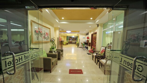 A hotel lobby with a reception desk, seating area, and a 'Welcome' mat. - Green Leaf Hotel (Yangon)