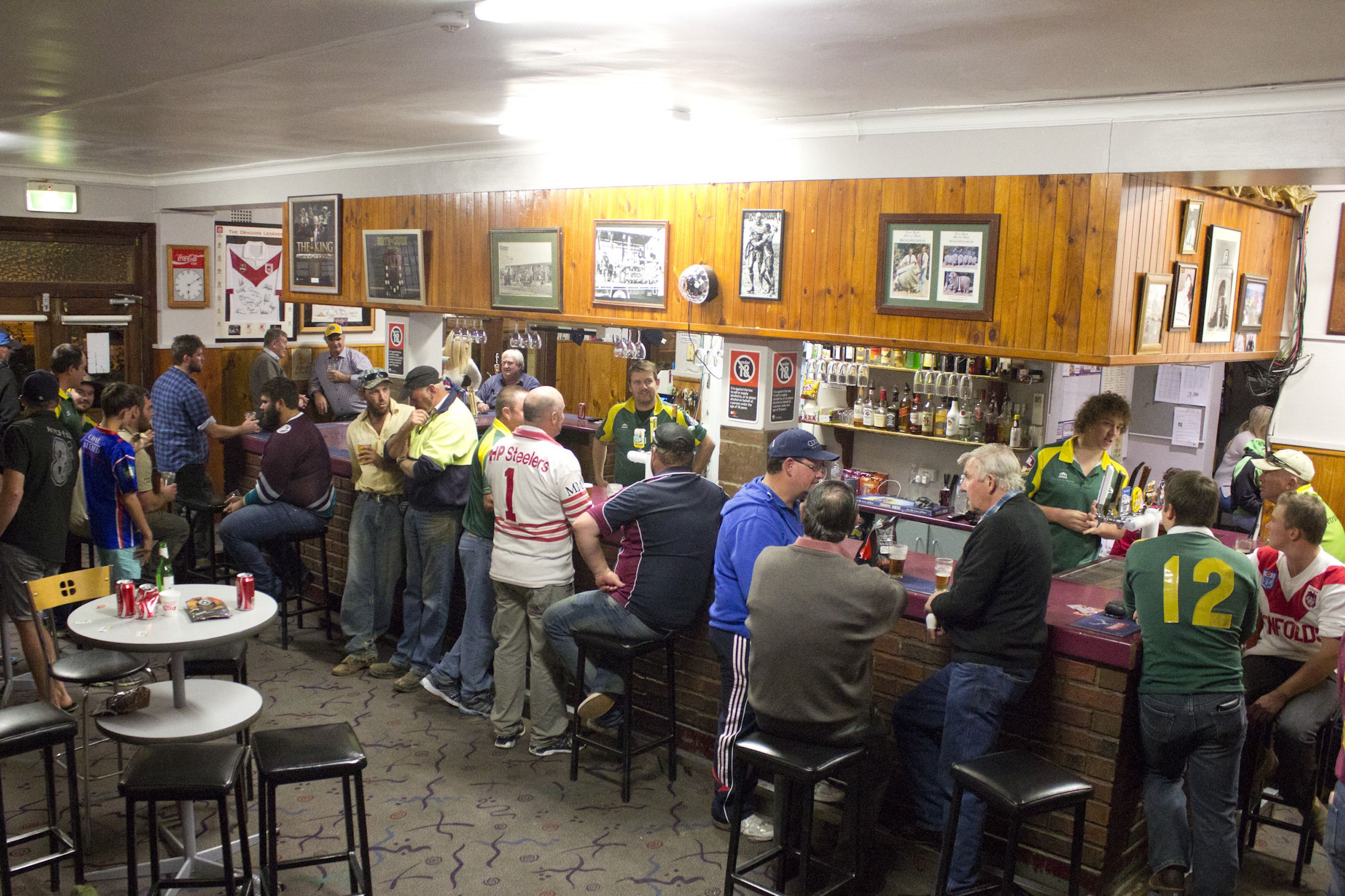 A crowded bar with wooden walls and a counter.