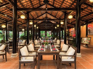 Un restaurante con terraza techada, mesas y sillas de madera.
