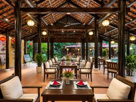 An indoor dining area with wooden tables and chairs, a ceiling fan, and hanging lanterns.