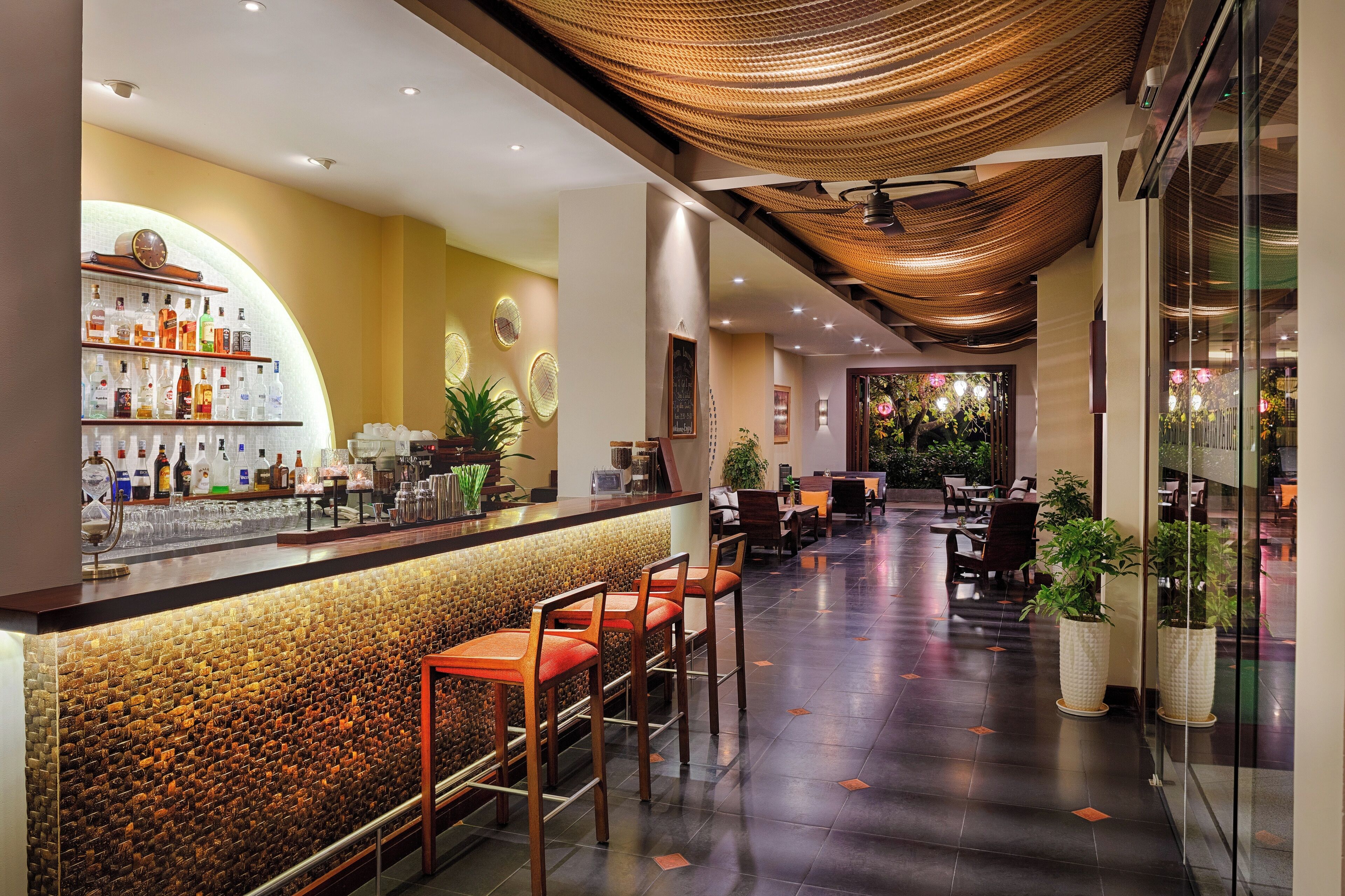 A hotel lobby with a bar area, seating, and potted plants.