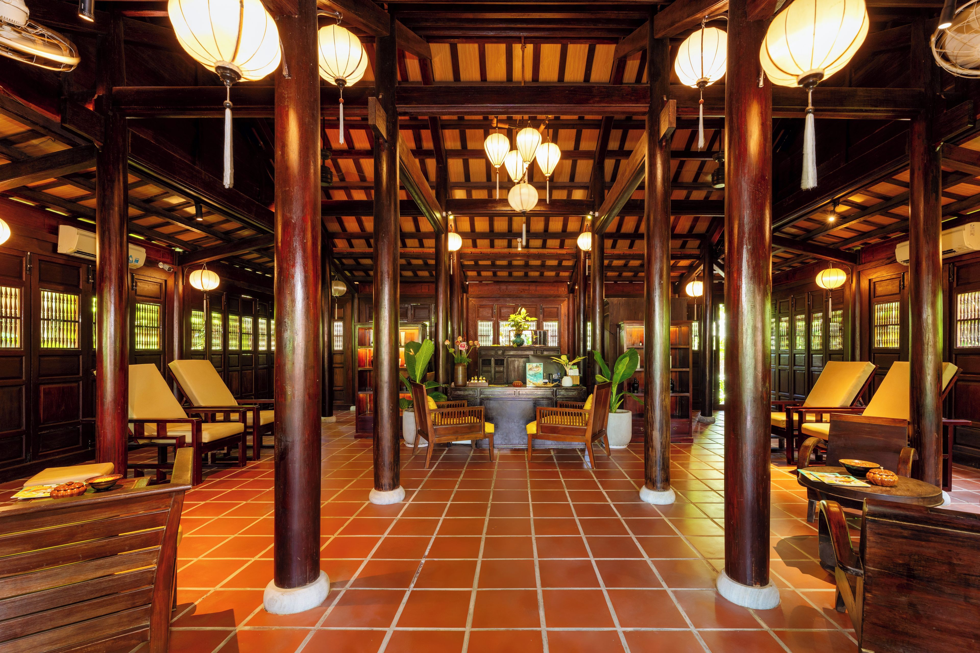 A traditional interior with wooden pillars, tiled flooring, and hanging lanterns.
