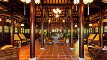 A traditional interior with wooden pillars, tiled flooring, and hanging lanterns.