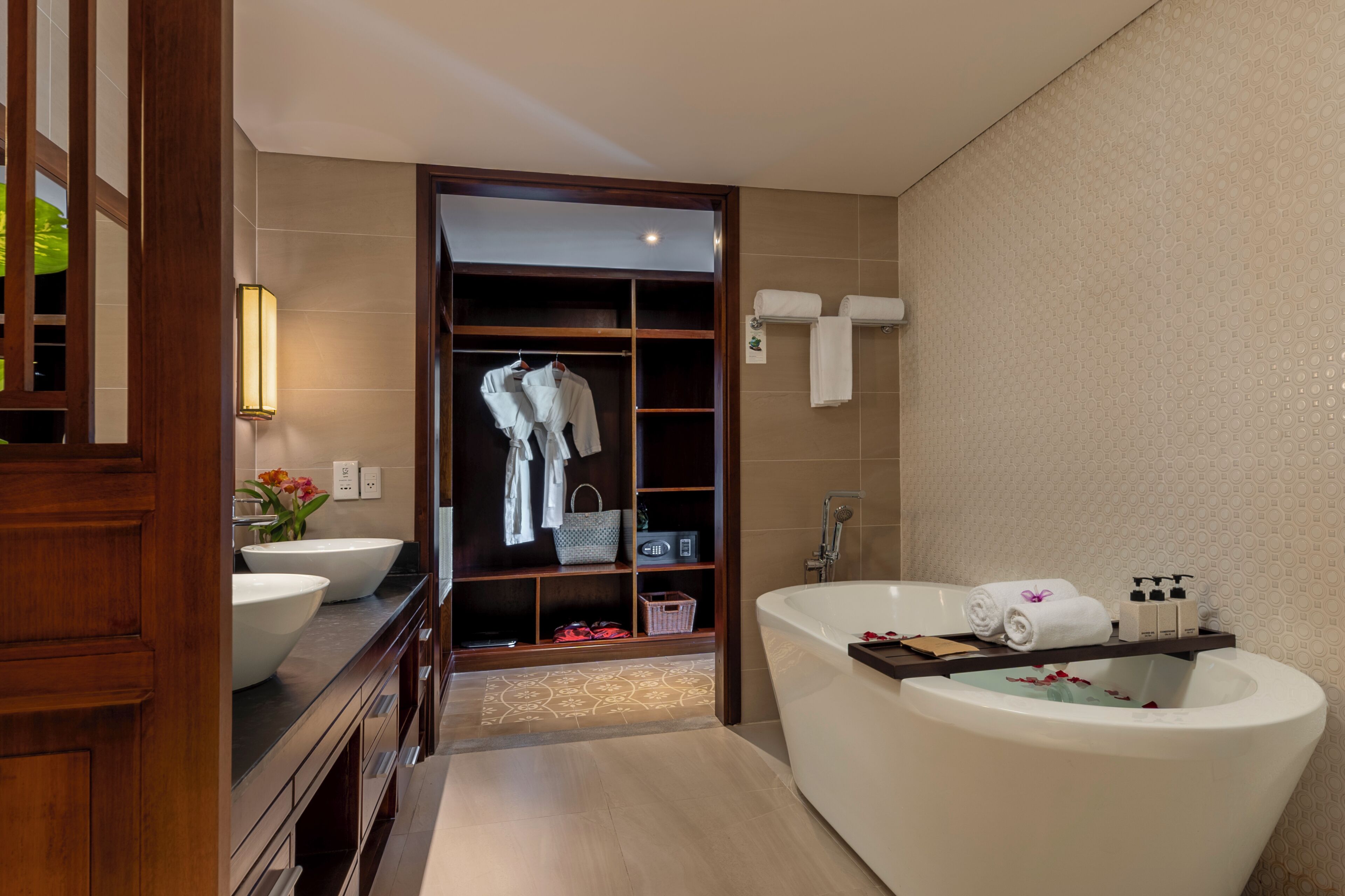 A modern bathroom with a large bathtub, a walk-in closet, and a vanity with a large sink.