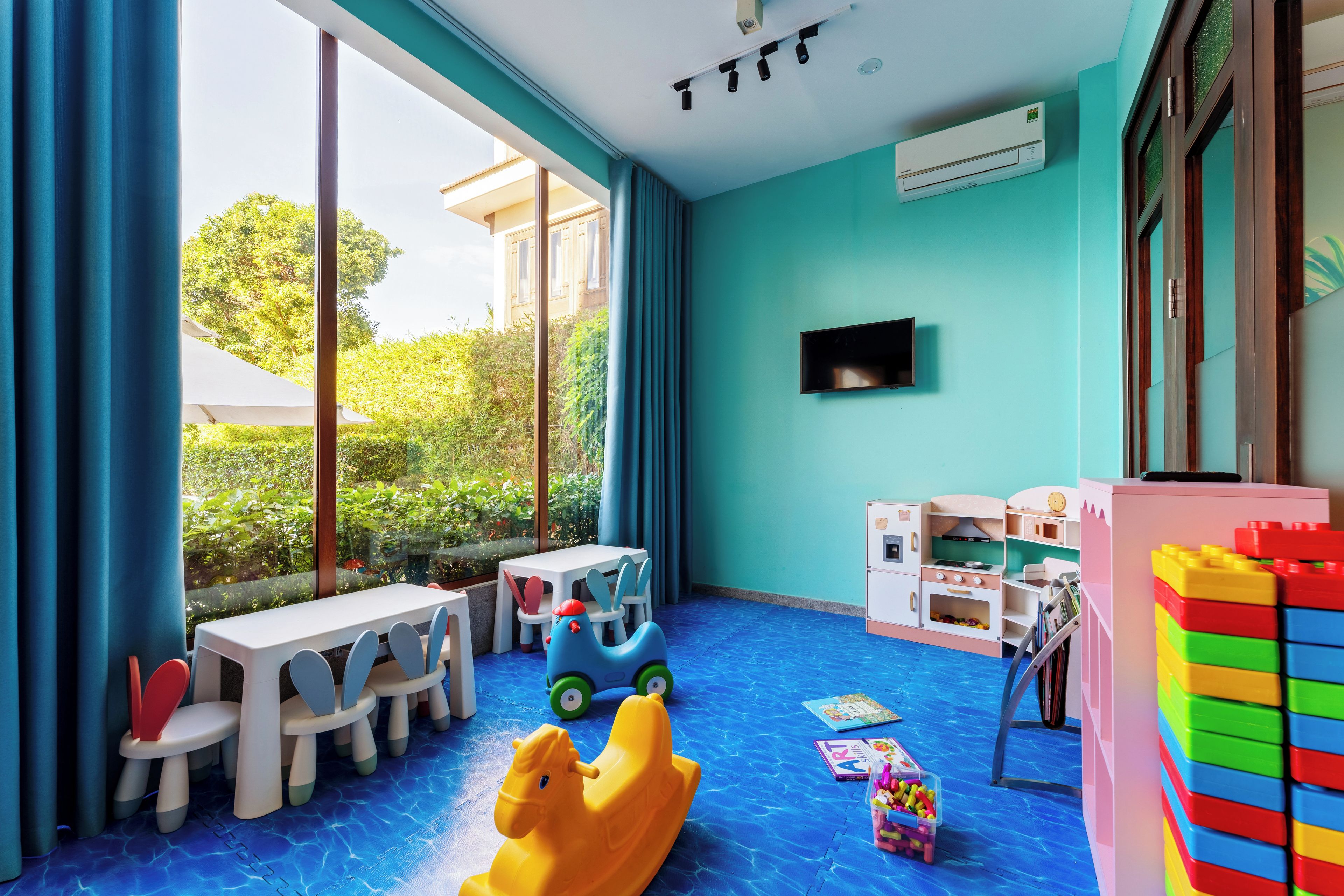 A children's playroom with a large window, a television, and various toys.