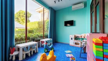 A children's playroom with a large window, a television, and various toys.