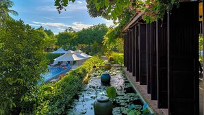 Un área de piscina tranquila con nenúfares, un espacio de descanso cubierto y una estructura de madera.