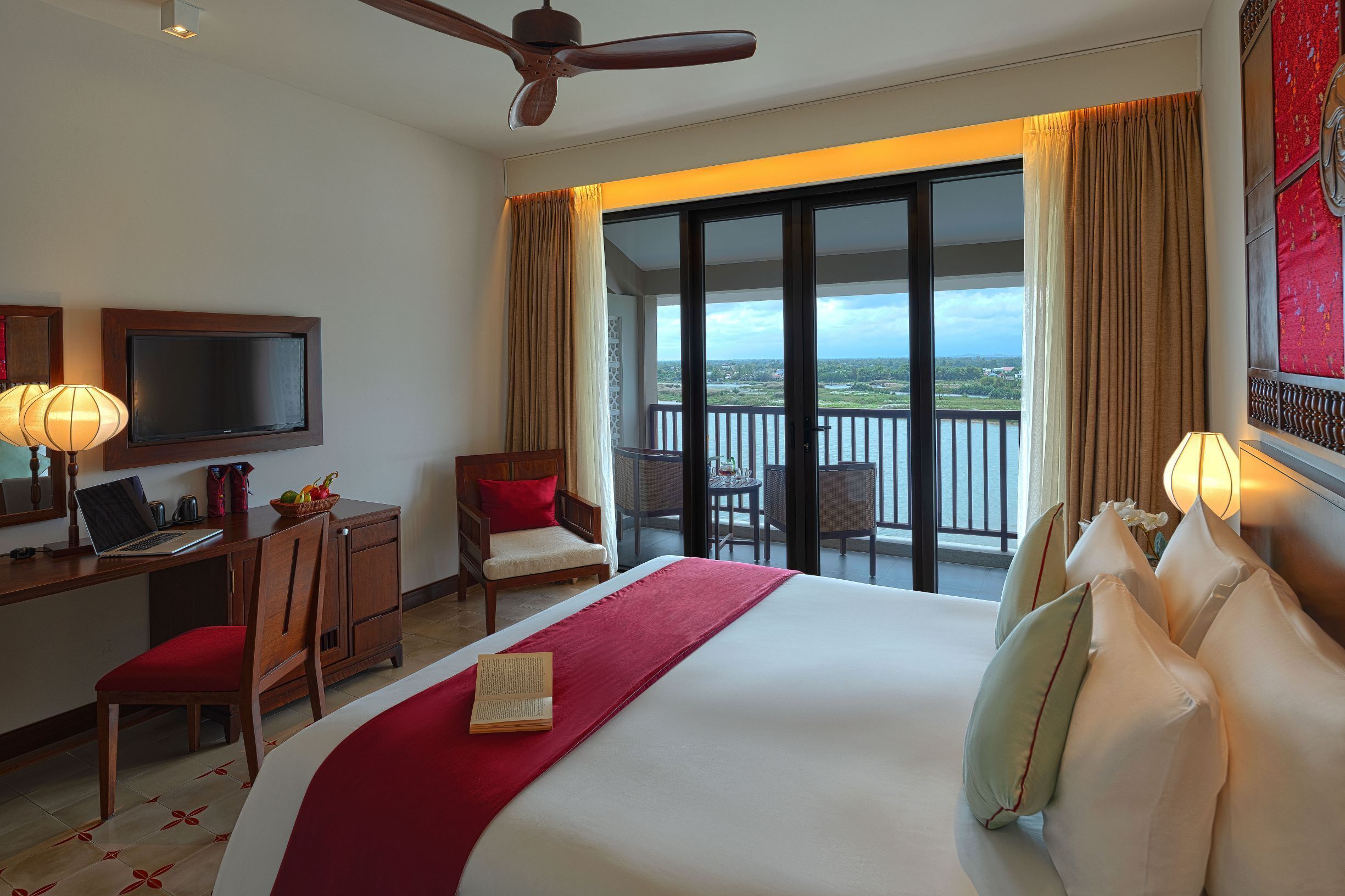 Une chambre d’hôtel équipée d’un lit, d’un bureau, d’un ordinateur portable, d’une chaise et d’un balcon avec vue.
