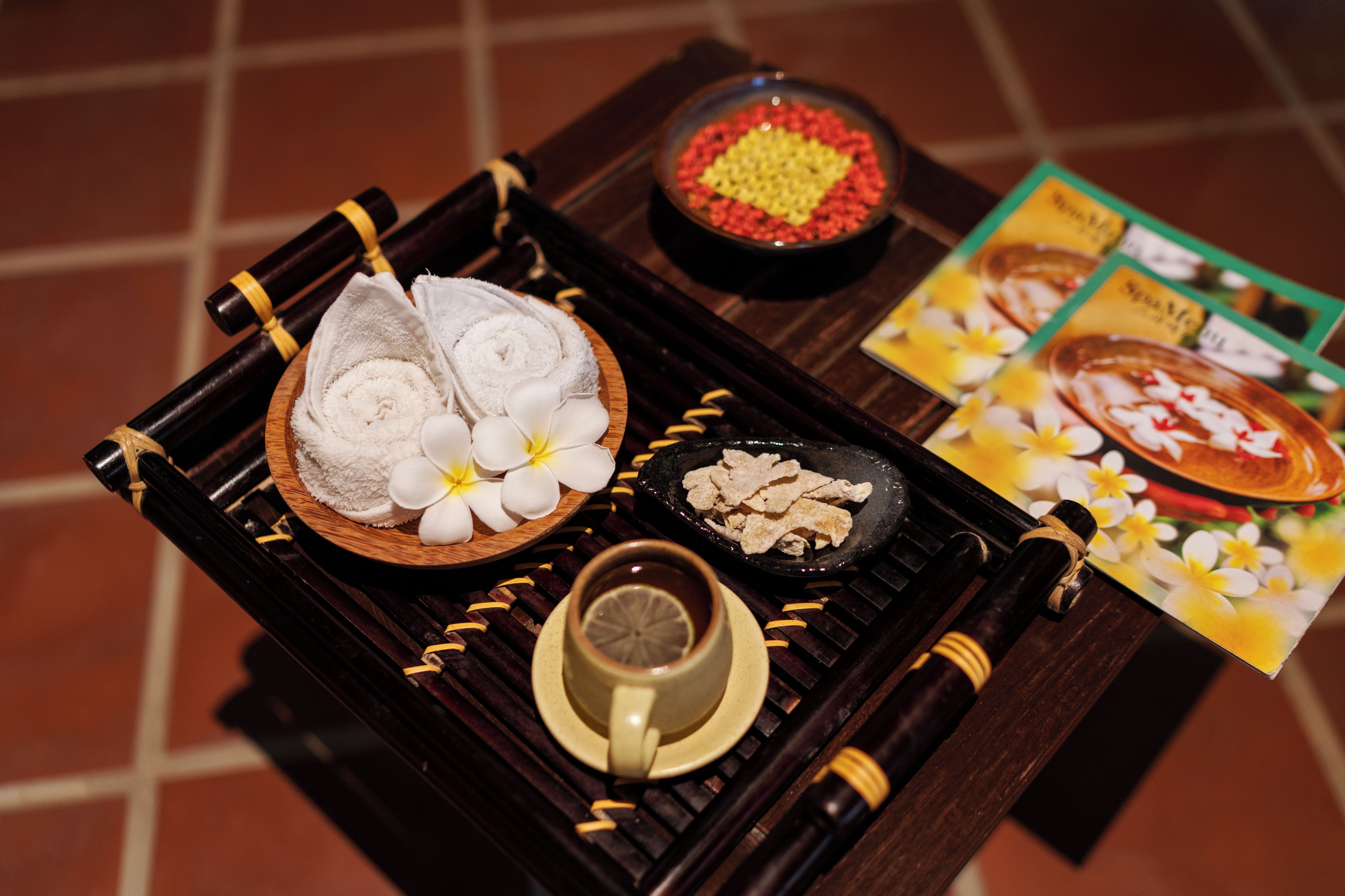 A tray with towels, a bowl of snacks, a cup, and a card.