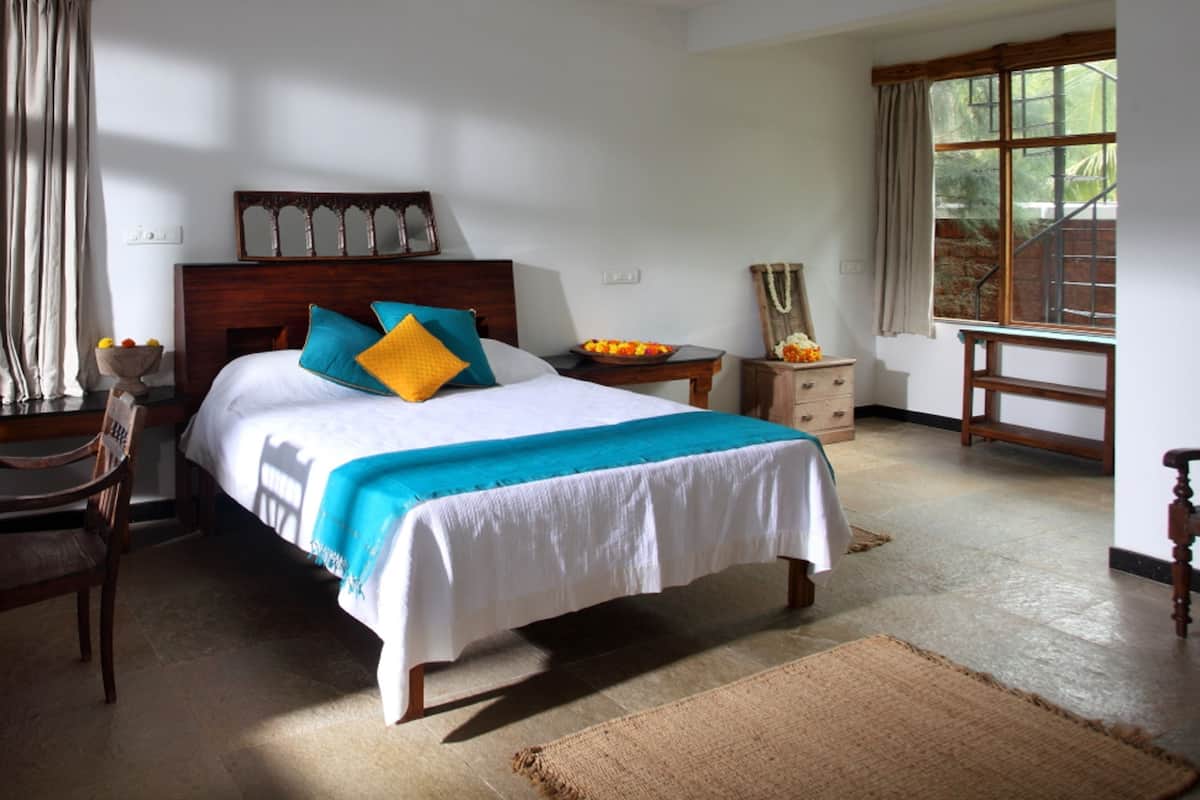 A neatly arranged bedroom with a large bed, bedside tables, a chair, and a window with curtains.
