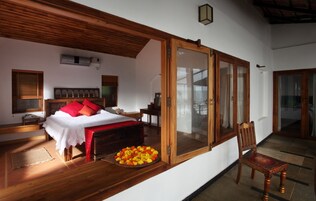 Un dormitorio con cama de madera, una mesita de noche, una silla y un amplio ventanal con vistas.