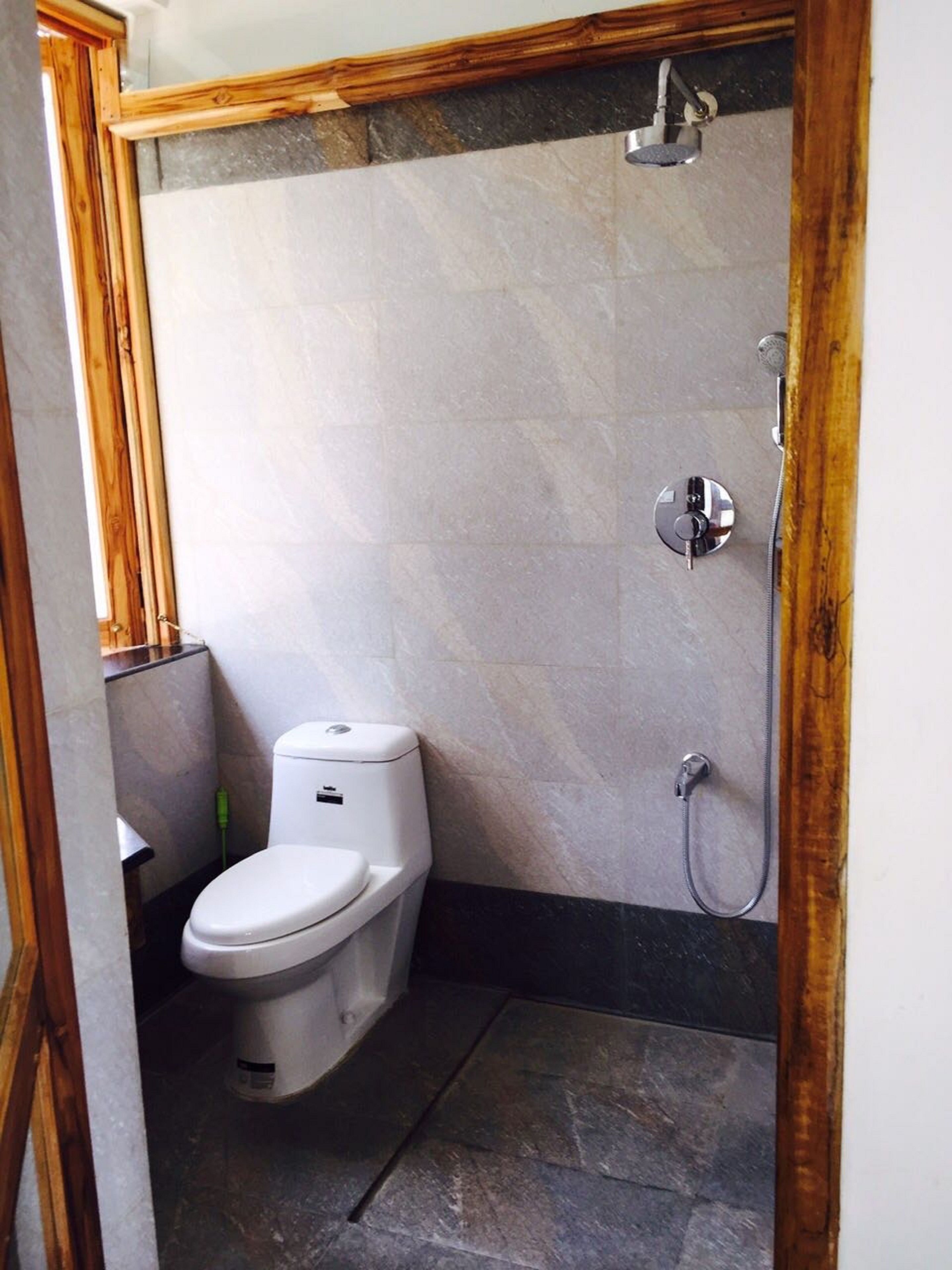 A small bathroom with a toilet, a shower, and a tiled floor.