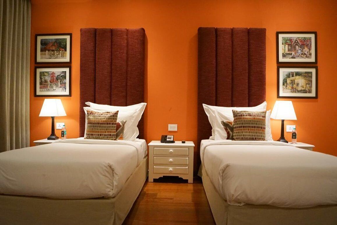 A hotel room with two beds, each with a pillow and a nightstand with a lamp.
