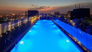 A rooftop infinity pool with a view of the city skyline at dusk. - The Waverly Hotel & Residences (Bengaluru)