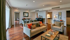 Amplia sala de estar con sofá, sillones y una mesa de centro. Se observa un comedor con una mesa y sillas, y una cocina al fondo.