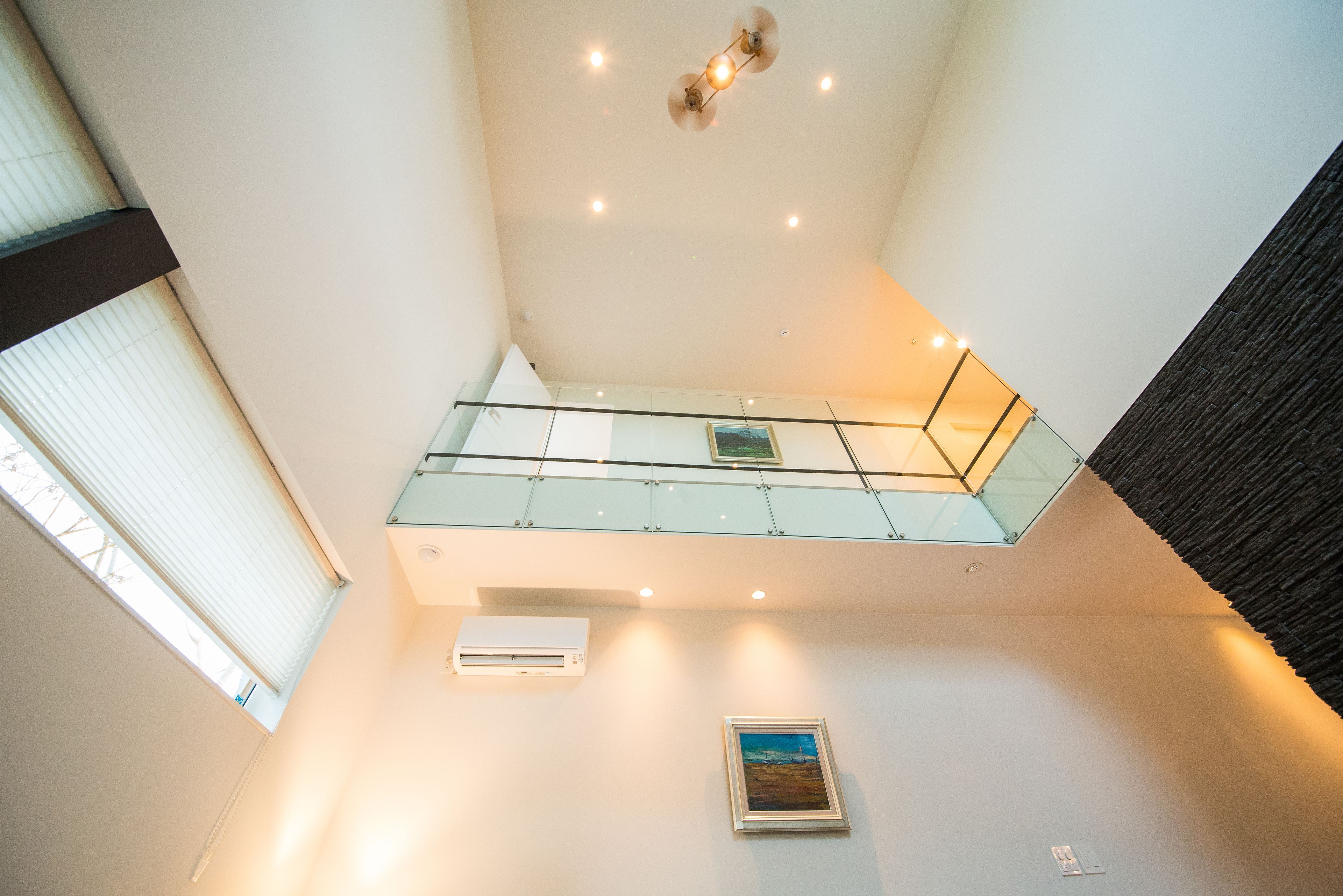 A modern interior with a glass balcony, recessed lighting, and a framed picture on the wall.