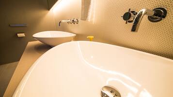 A bathroom with a large white bathtub, a white sink, and a yellow soap dispenser.