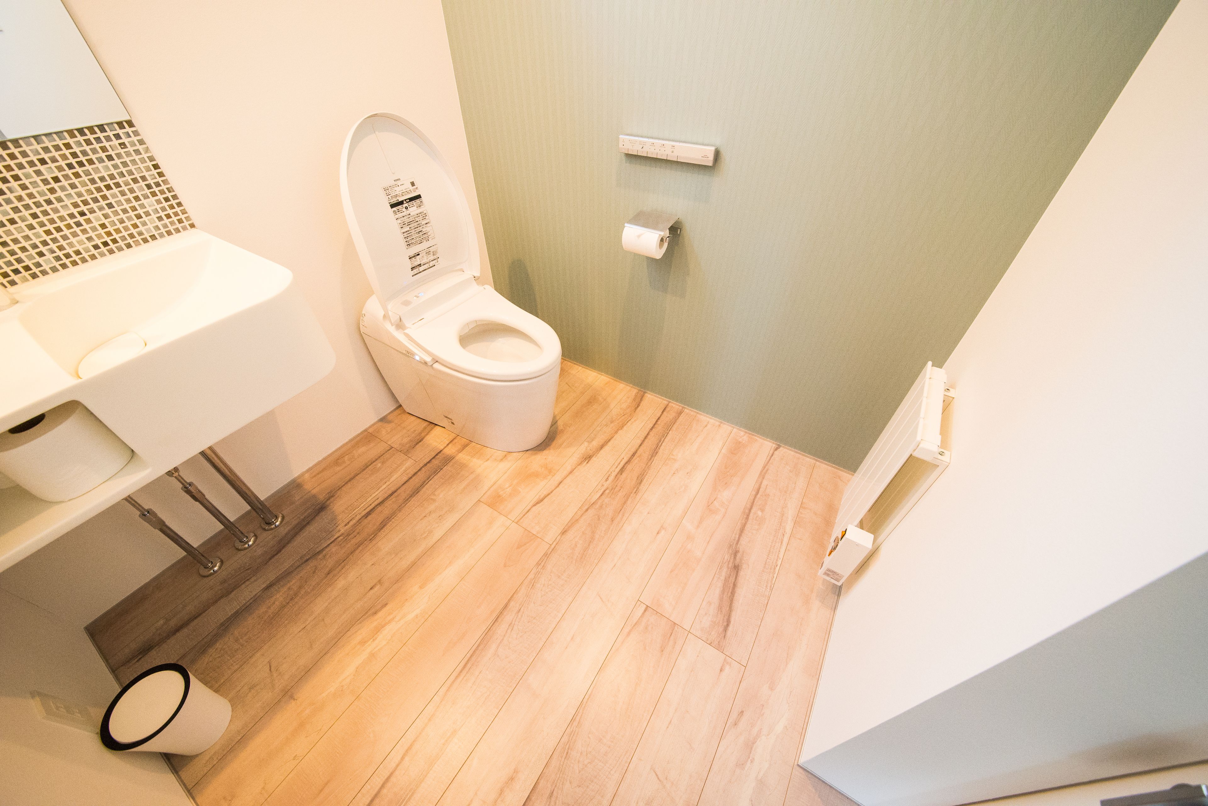 A bathroom with a toilet, sink, and a small trash bin.