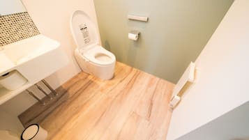 A bathroom with a toilet, sink, and a small trash bin.