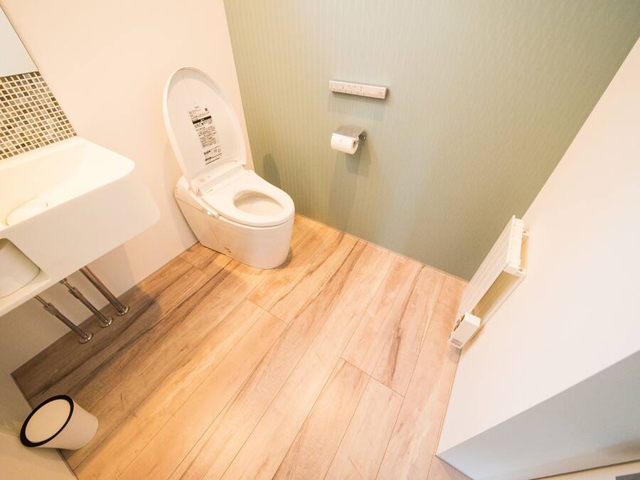 A bathroom with a toilet, sink, and a small trash bin.