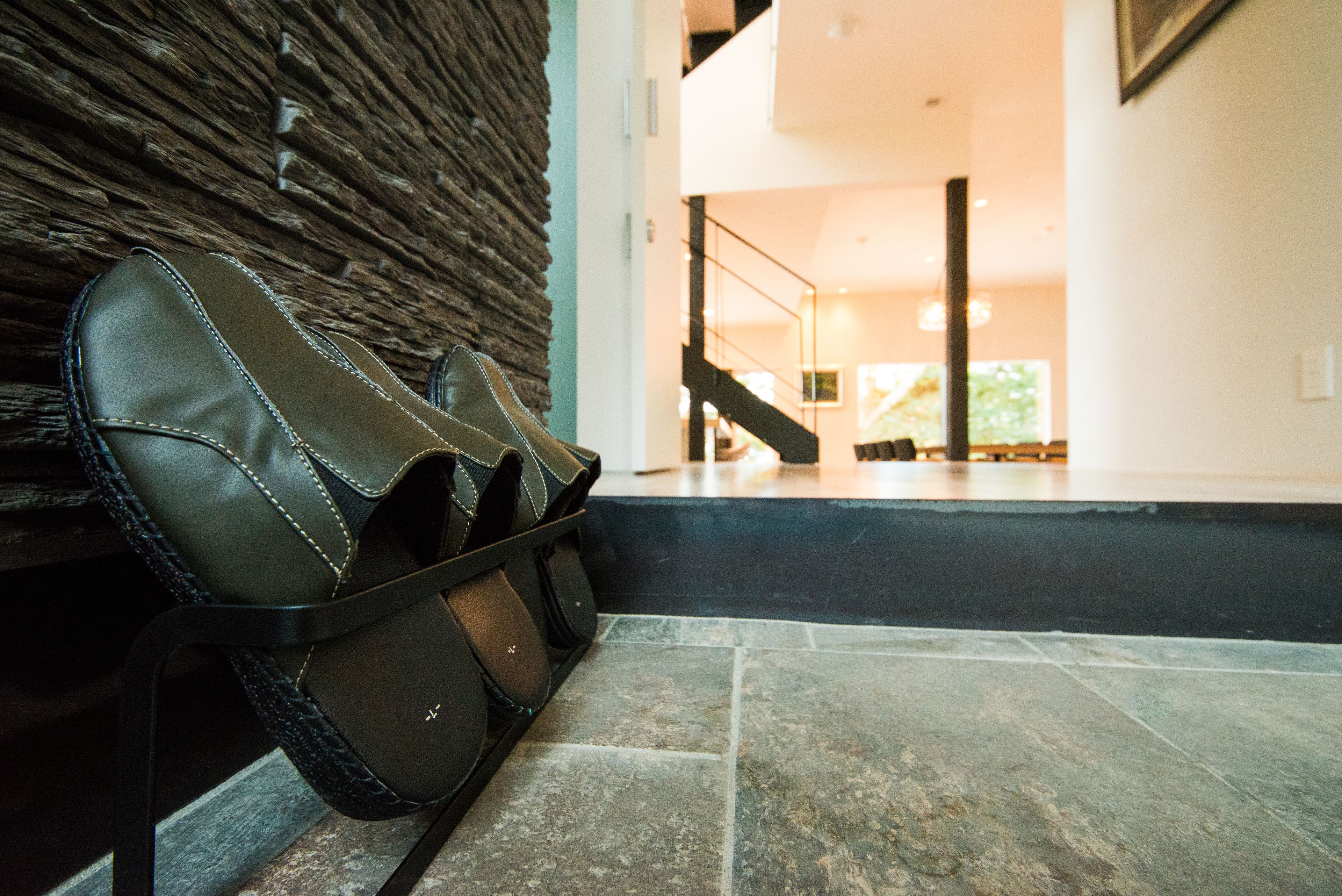 A pair of leather shoes on a bench with a stone wall and a staircase leading to an upper level.