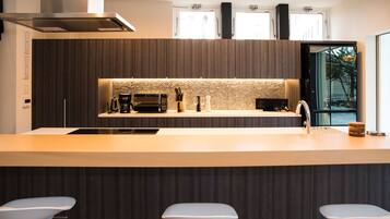 Una cocina moderna con una isla central, muebles oscuros y vistas al exterior a través de amplios ventanales.