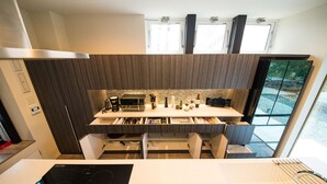 A modern kitchen with a built-in stove, white countertops, and dark wooden cabinets. - La Cachette (Hakodate)
