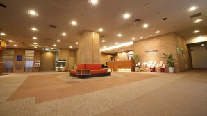 A hotel lobby with a reception desk, a sofa, and a staircase.