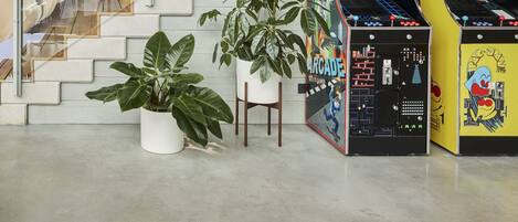 A staircase with a mural, arcade games, and potted plants.