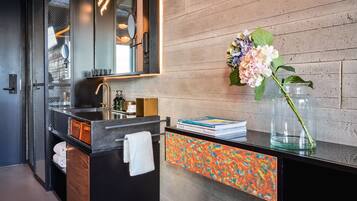 Un baño moderno con un tocador negro, un espejo grande y un jarrón decorativo con flores.