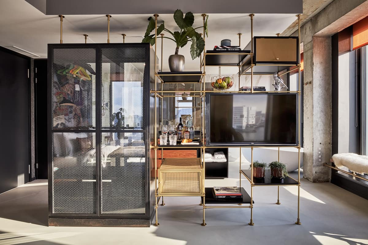 A modern interior with a glass partition, a gold-framed shelving unit, and a large window.