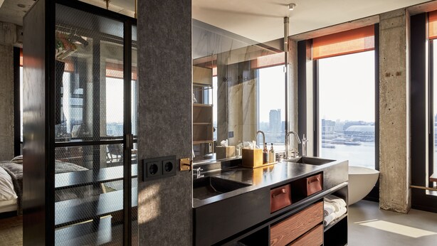 Un baño moderno con un espejo grande, una bañera y vistas a la ciudad.