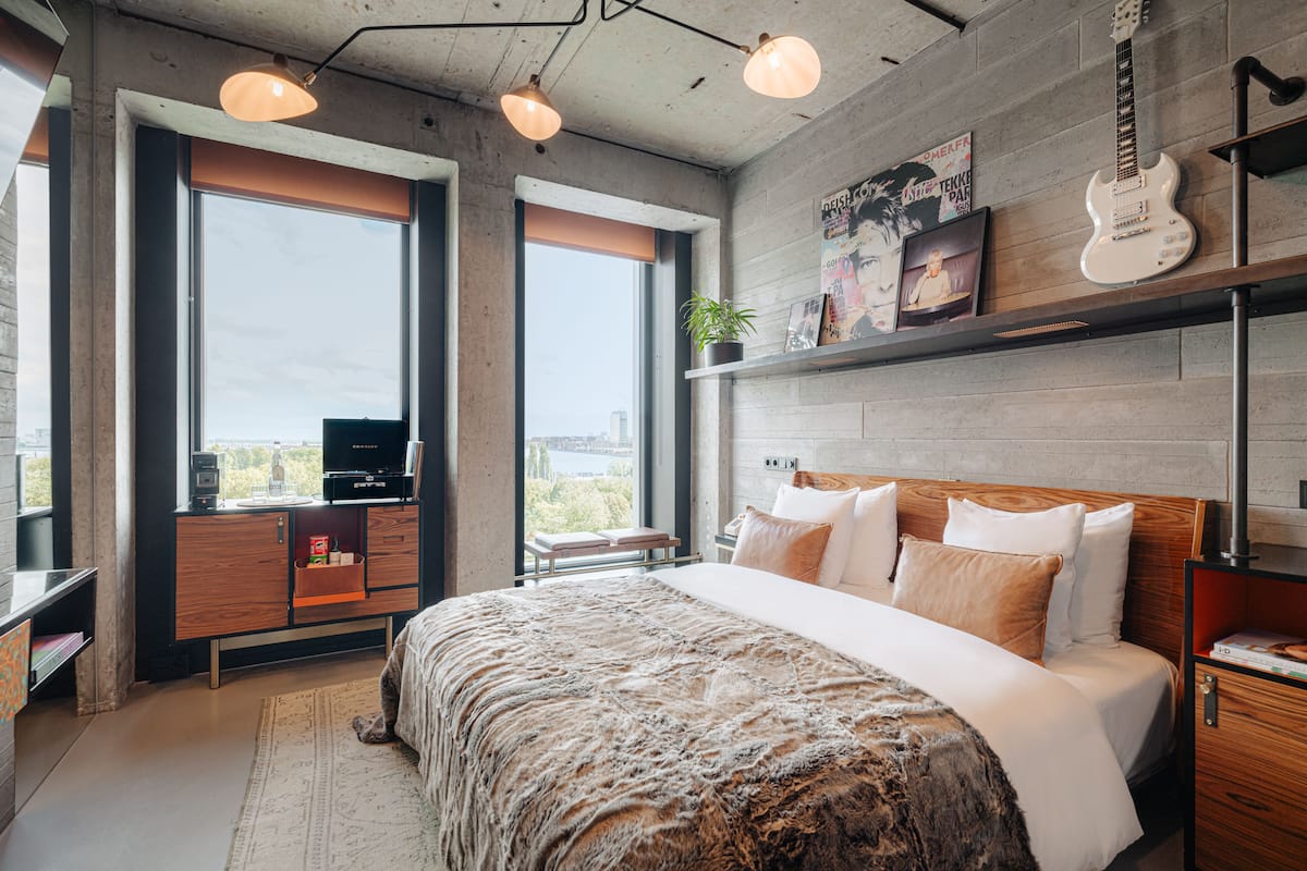 A modern bedroom with a large bed, a desk, and a TV.