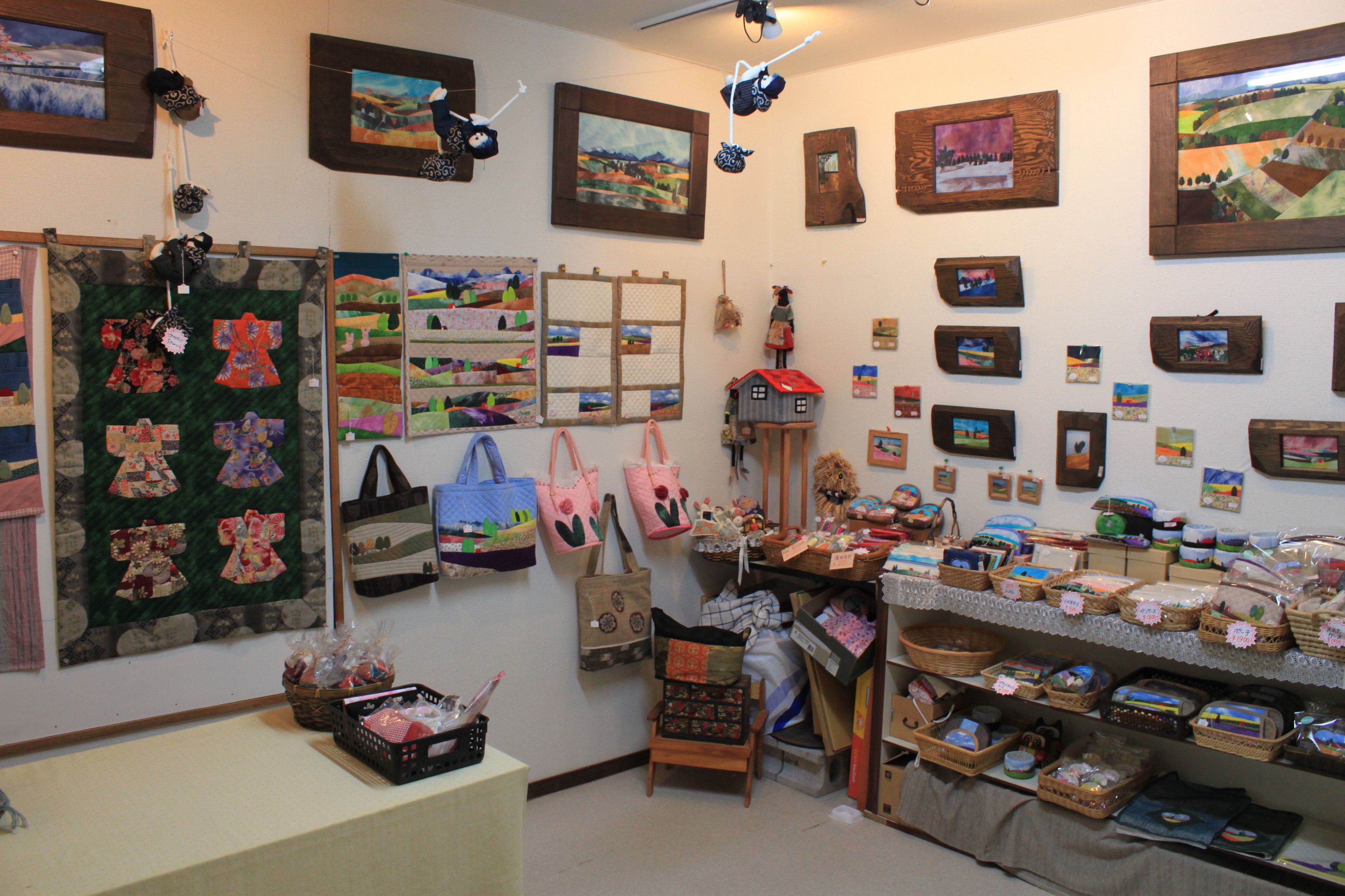 A craft store with various handmade items, including quilts, baskets, and bags displayed on shelves and walls.