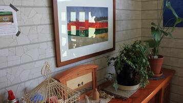 A framed artwork on a wall, a wooden cabinet with decorative items, and a potted plant on a wooden surface.
