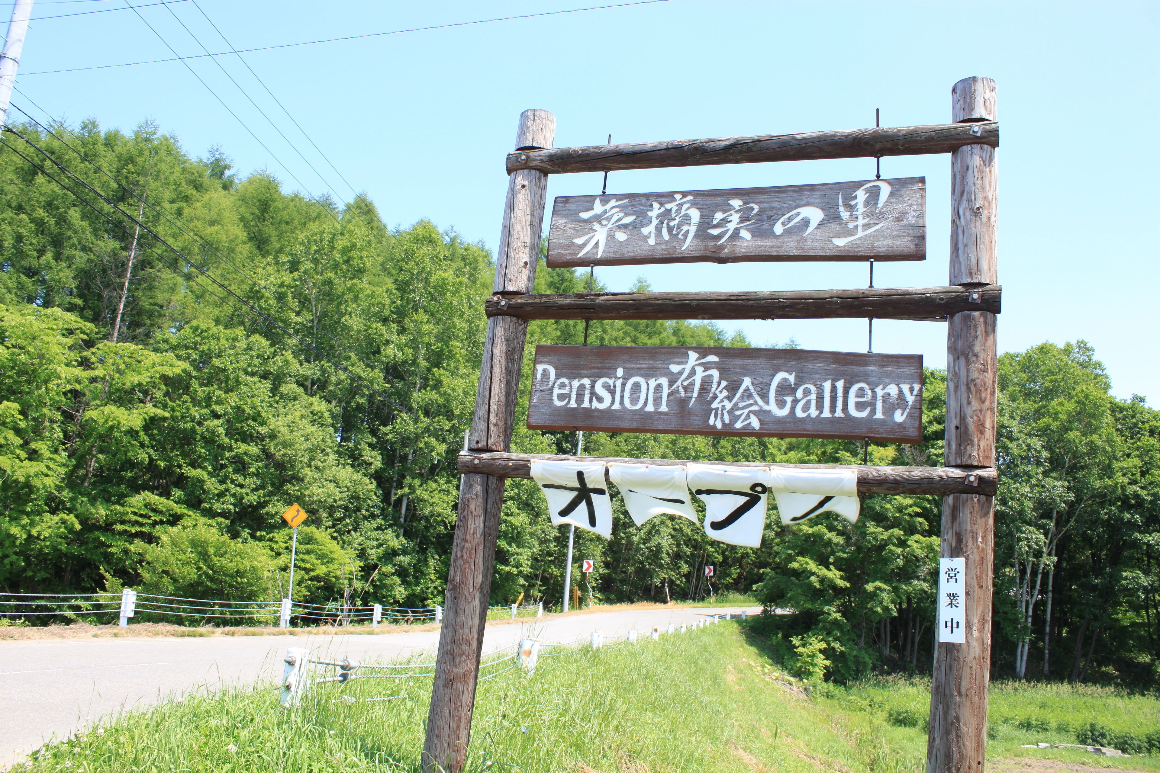 A wooden sign with Japanese characters and "Pension Gallery" written in English.