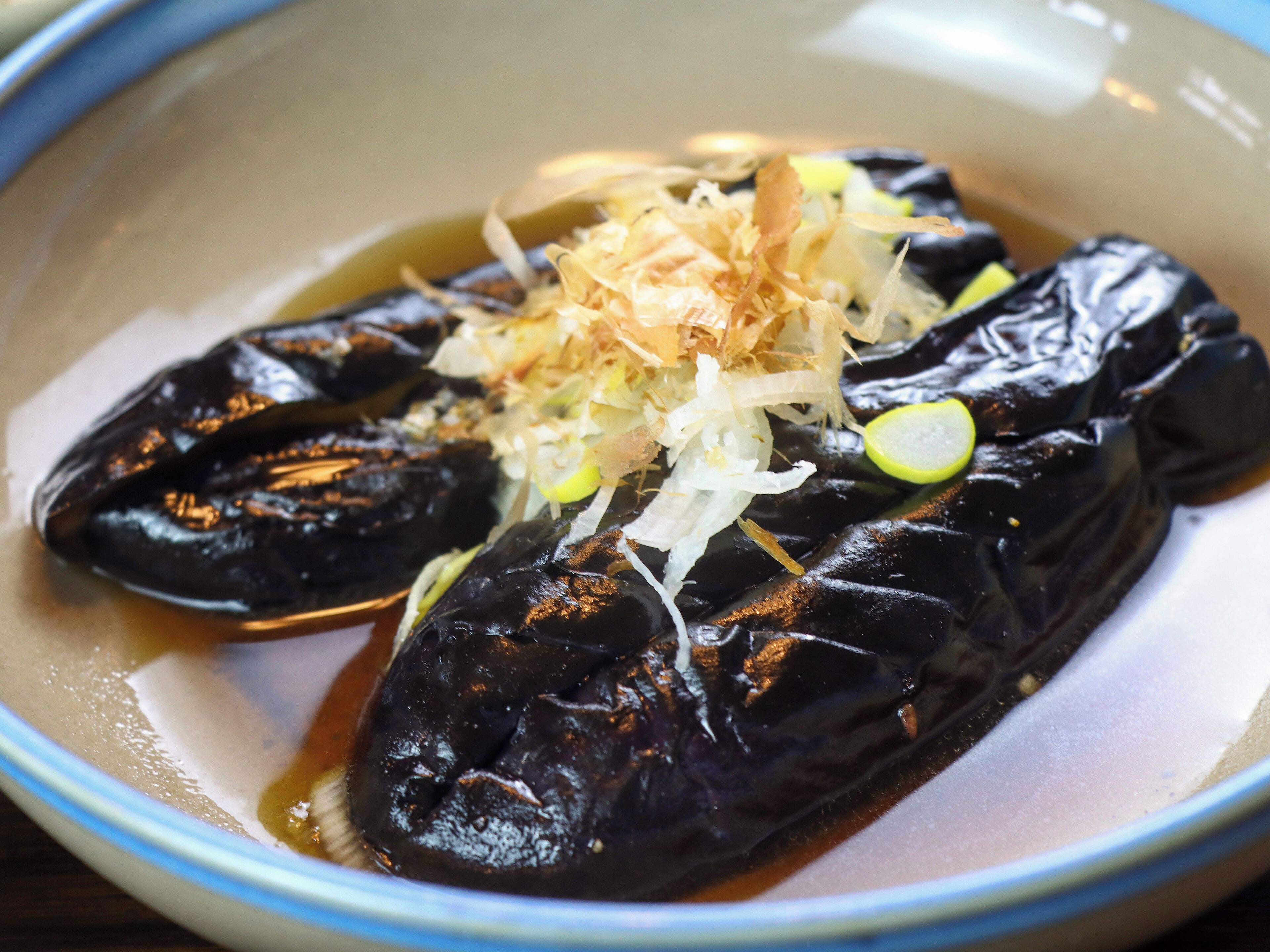 A bowl of grilled eel with shredded daikon and green onions on a plate.