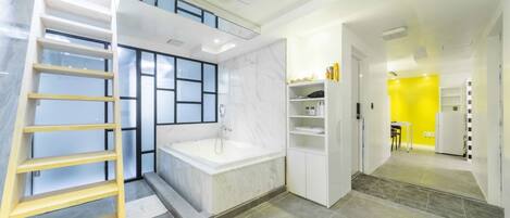 A modern bathroom with a bathtub, a wooden ladder, and a marble wall.