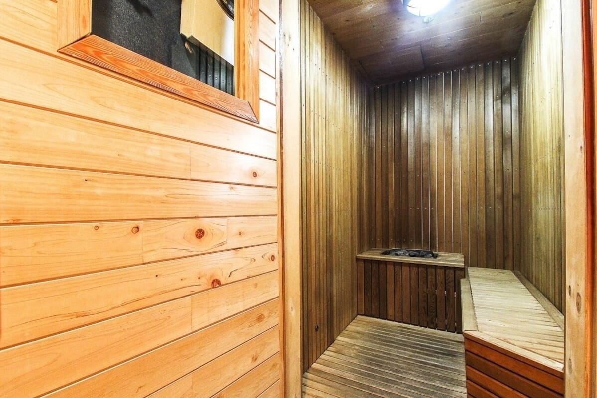 A wooden sauna with a bench and a small table.