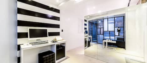Une pièce moderne et minimaliste avec un mur à rayures, un bureau avec un ordinateur et une grande fenêtre.