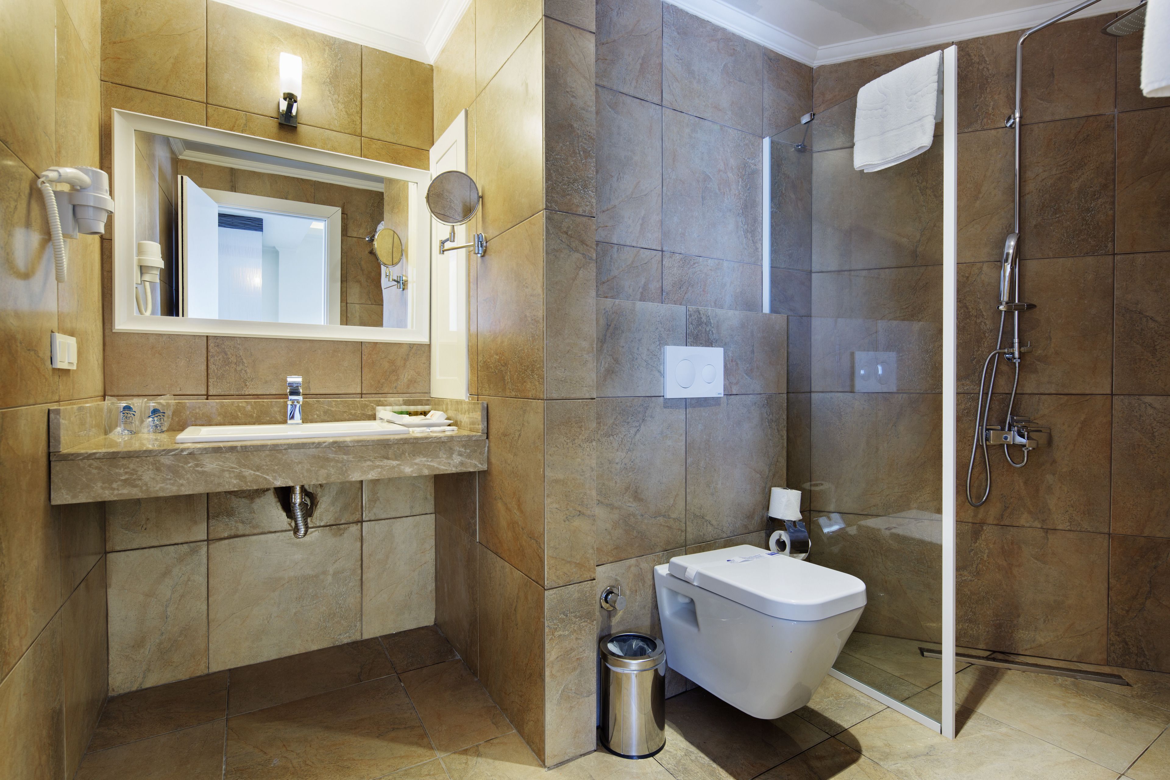 A modern bathroom with a large mirror, a sink, a toilet, and a shower.