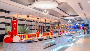 Un vestíbul d'hotel modern amb una recepció de marbre, diverses zones de restauració i lluminàries contemporànies.