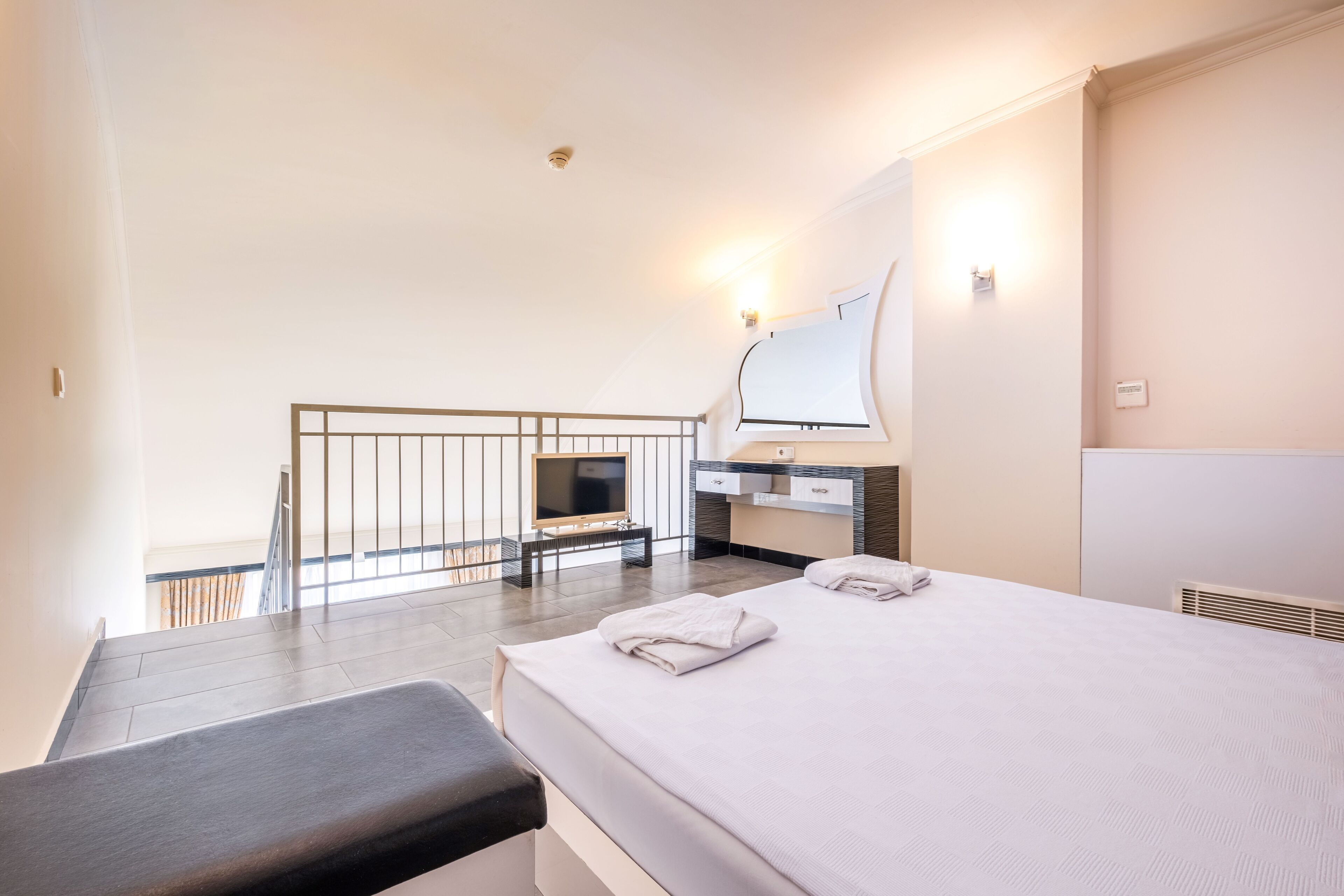 Una habitación de hotel con cama, escritorio, silla, televisor y baño.