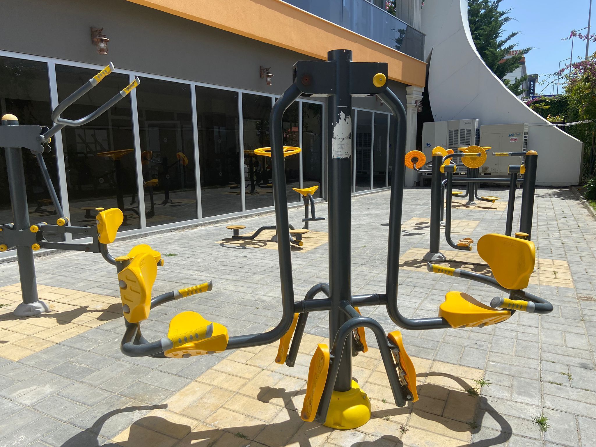 Outdoor exercise equipment near a building with large windows.