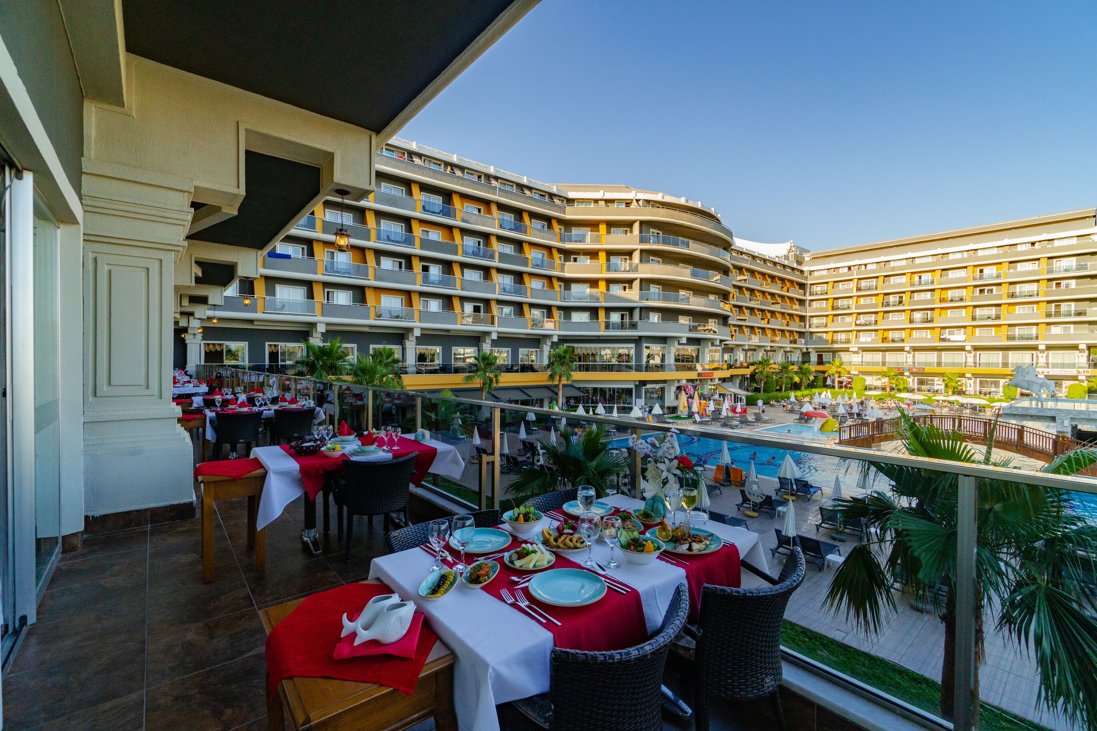 A hotel with multiple balconies, outdoor dining areas, and a swimming pool.